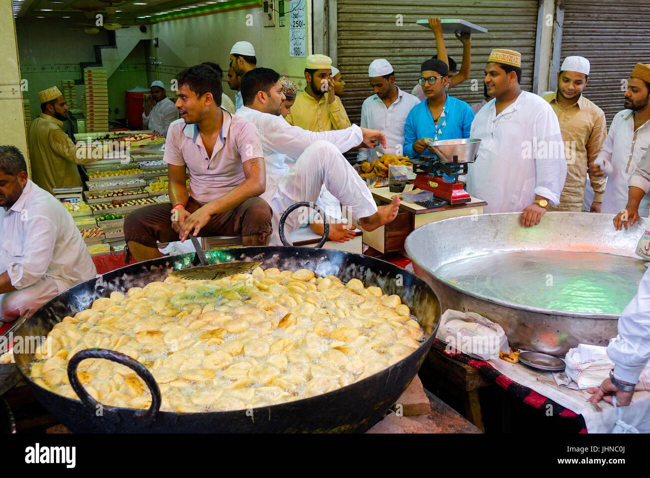 Uomo kachori frittura in tondo grande padella ovvero Karahi, per la festa musulmana di Eid al-fitr, gli acquirenti in attesa di essere preparato Foto Stock