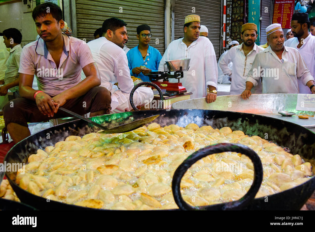 Uomo kachori frittura in tondo grande padella ovvero Karahi, per la festa musulmana di Eid al-fitr, gli acquirenti in attesa di essere preparato Foto Stock
