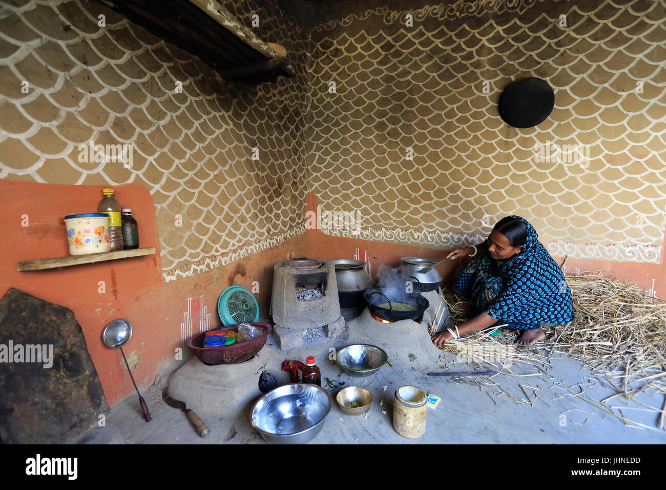 Una donna cuochi dentro la sua casa al villaggio Tikoil in Nachole upazila di Chapainawabganj distretto del Bangladesh. Più di cinquanta case in questo villaggio un Foto Stock