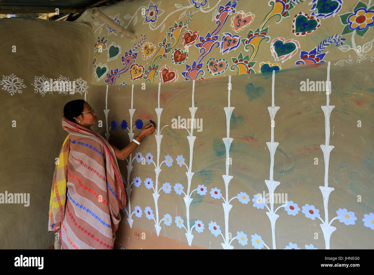 Una donna richiama i motivi tradizionali su una parete della sua casa di villaggio Tikoil in Nachole upazila di Chapainawabganj distretto del Bangladesh. Più di fift Foto Stock