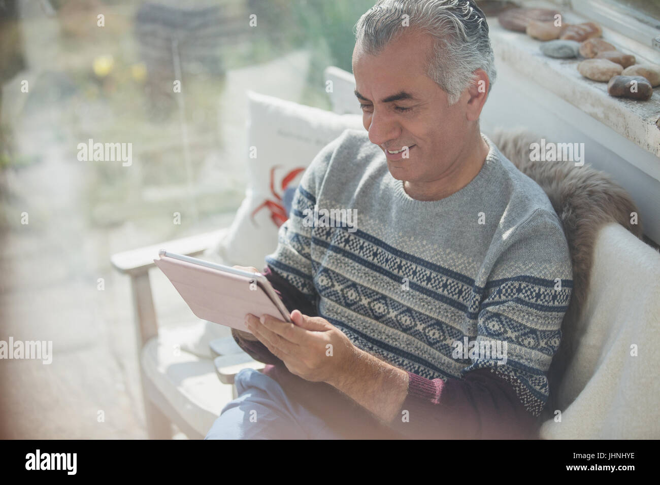 Senior uomo con tavoletta digitale sul portico di Sun Foto Stock