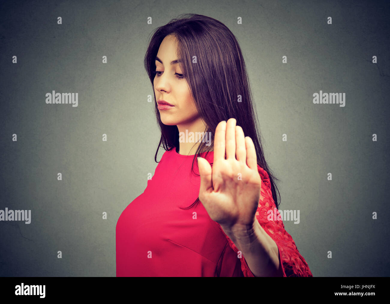 Closeup ritratto arrabbiato Donna che parla a mano gesto con il palmo verso l'esterno isolato muro grigio Sfondo. Negativo emozione umana il linguaggio del corpo Foto Stock