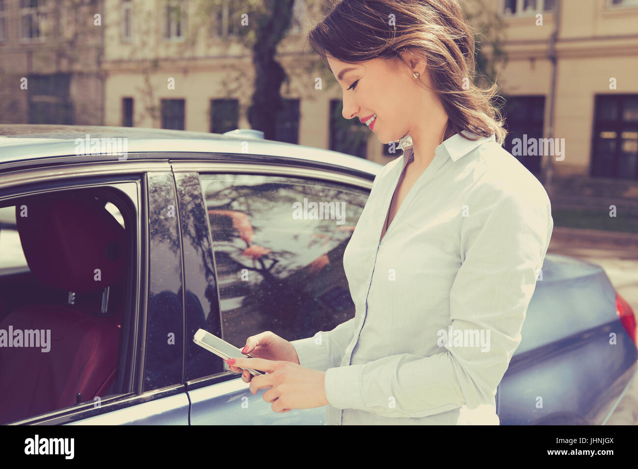 Telefono mobile app per i proprietari dei veicoli concept. Donna che utilizza smart phone per controllare lo stato di controllo, la sua nuova vettura Foto Stock