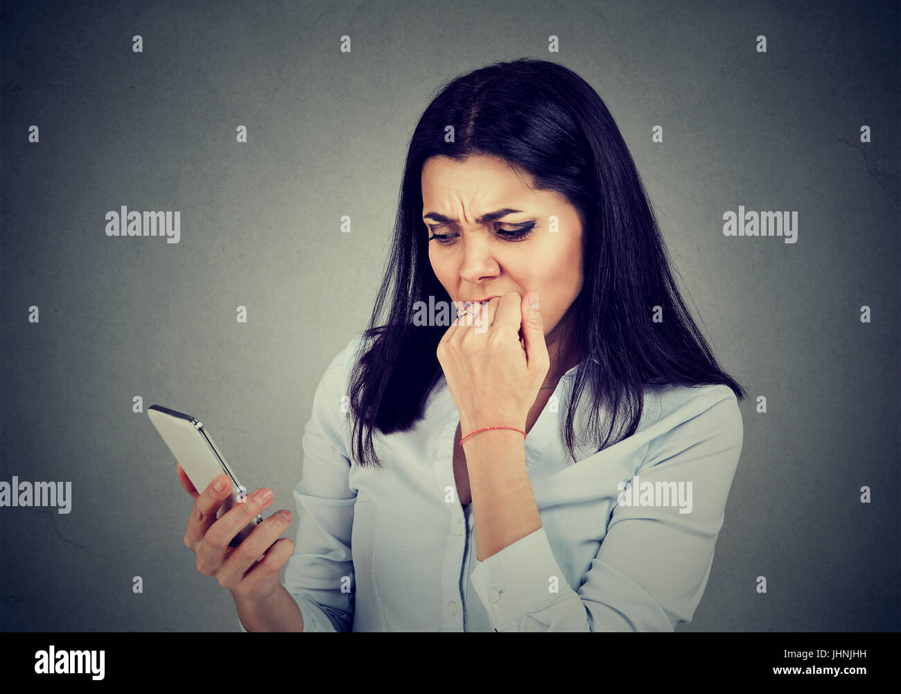 Arrabbiato ansiosi donna guardando le applicazioni nel telefono cellulare isolato su sfondo grigio Foto Stock