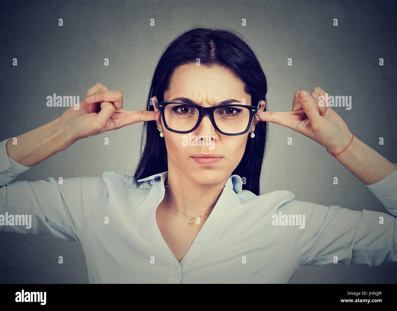 Arrabbiato donna collegando le sue orecchie con le dita Foto Stock