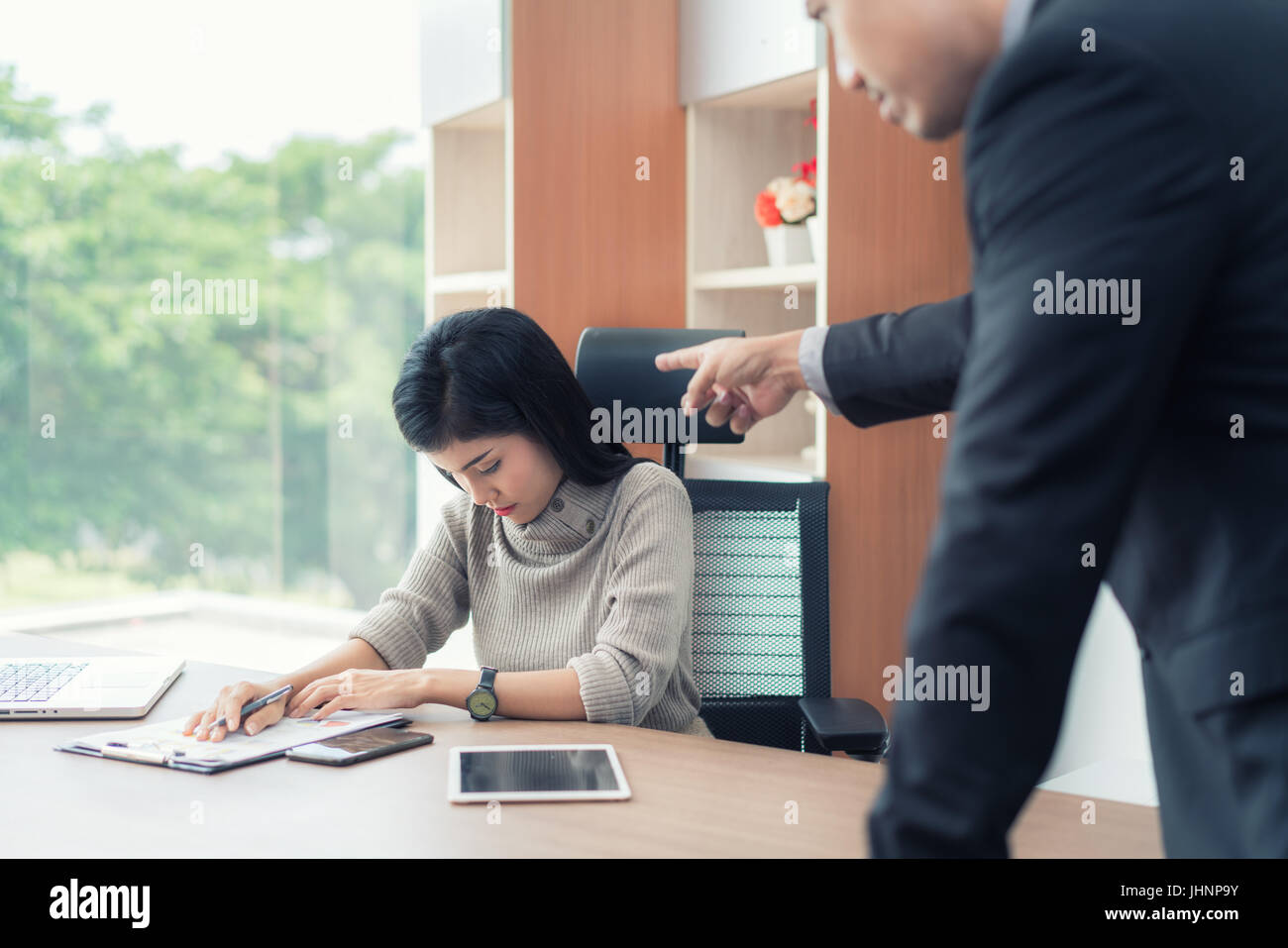 Segretario asiatica sottolinea quando il suo manager è il puntamento e viene imputato per un lavoro difettoso. Segretario e manager in ufficio. Foto Stock
