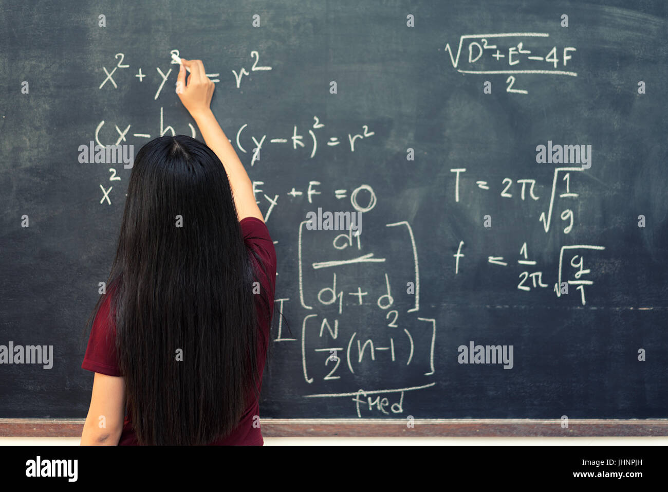 Bella asiatica studente che scrive sulla lavagna con gesso in aula. Foto Stock