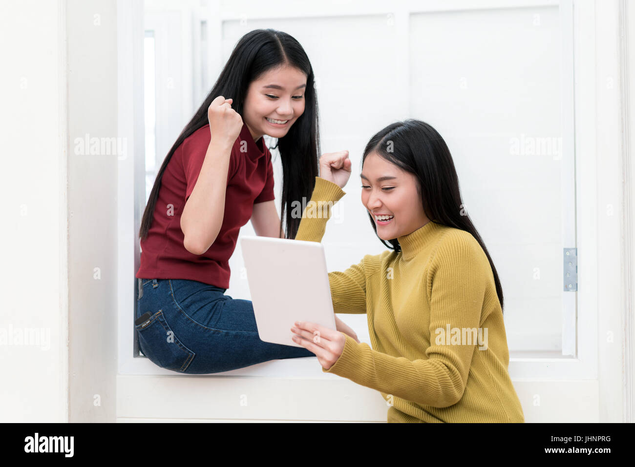 Due Asian gli studenti universitari in un utilizzo di tablet e piacere in universitari. Successo il concetto di istruzione. Foto Stock