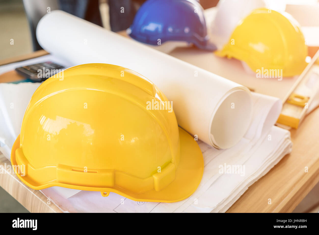 Ingegnere Casco giallo, calcolatrice, livello e disegni di progetto su office tabella. Ingegnere di sicurezza concetto. Foto Stock