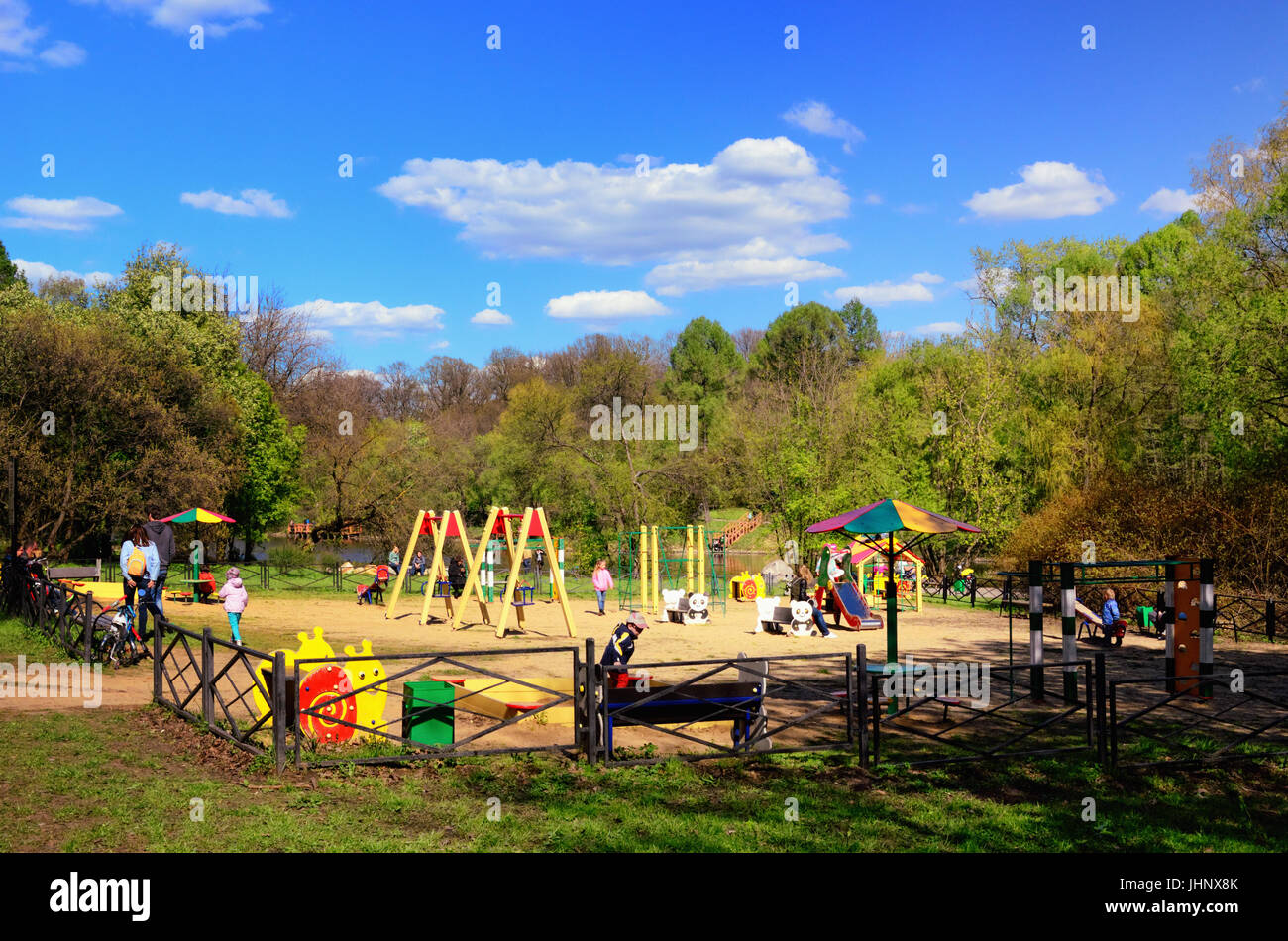 Parco giochi per bambini in un parco verde in maggio con giochi per bambini e genitori Foto Stock