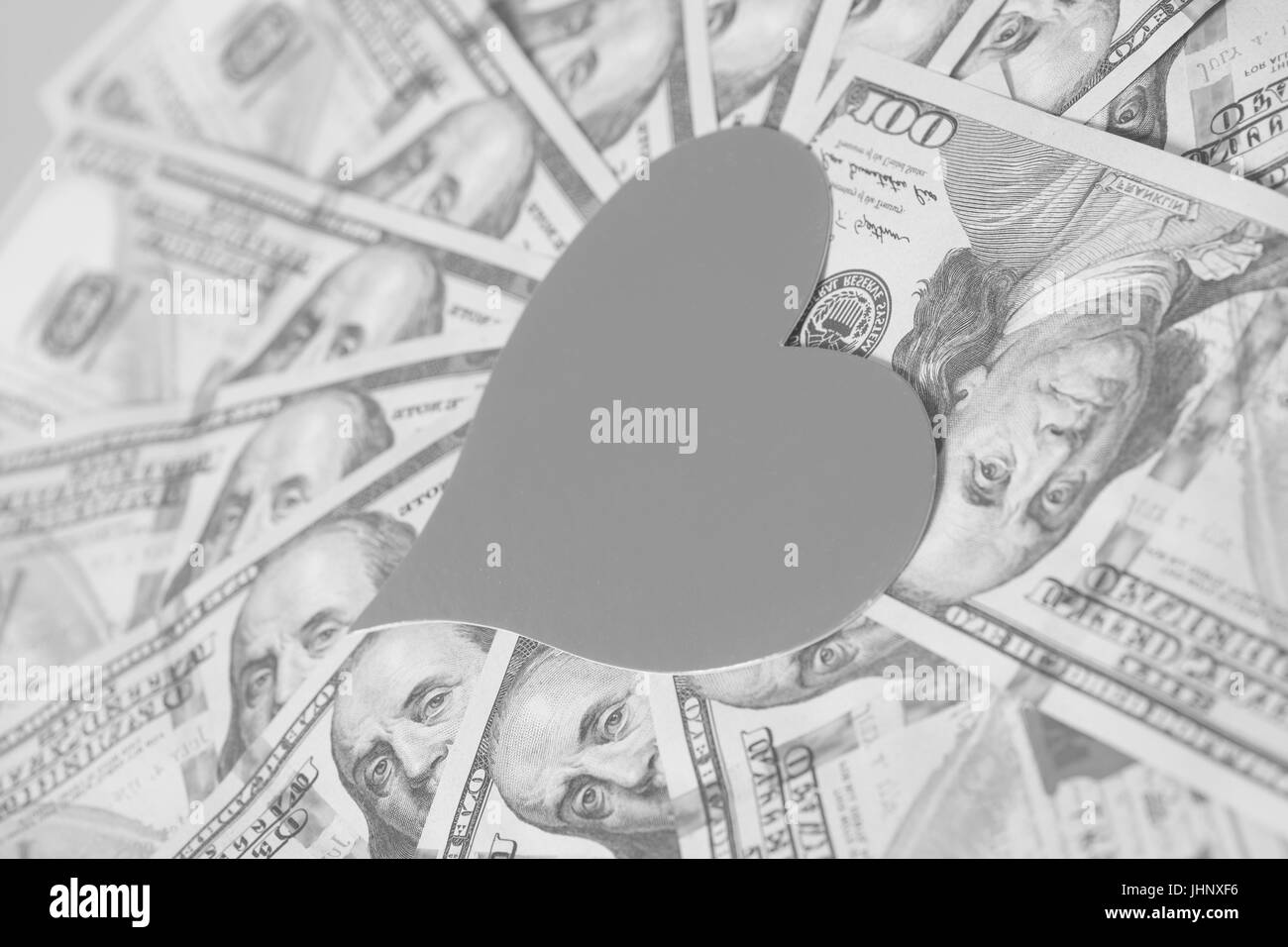 Cuore di carta e centinaia di fatture del dollaro su grigio Foto Stock