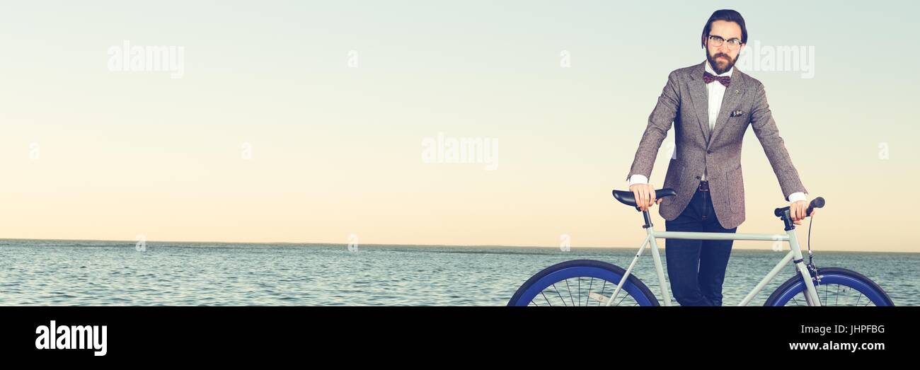 Composito Digitale dell uomo millenario con il filtro bow tie e bicicletta contro orizzonte Foto Stock
