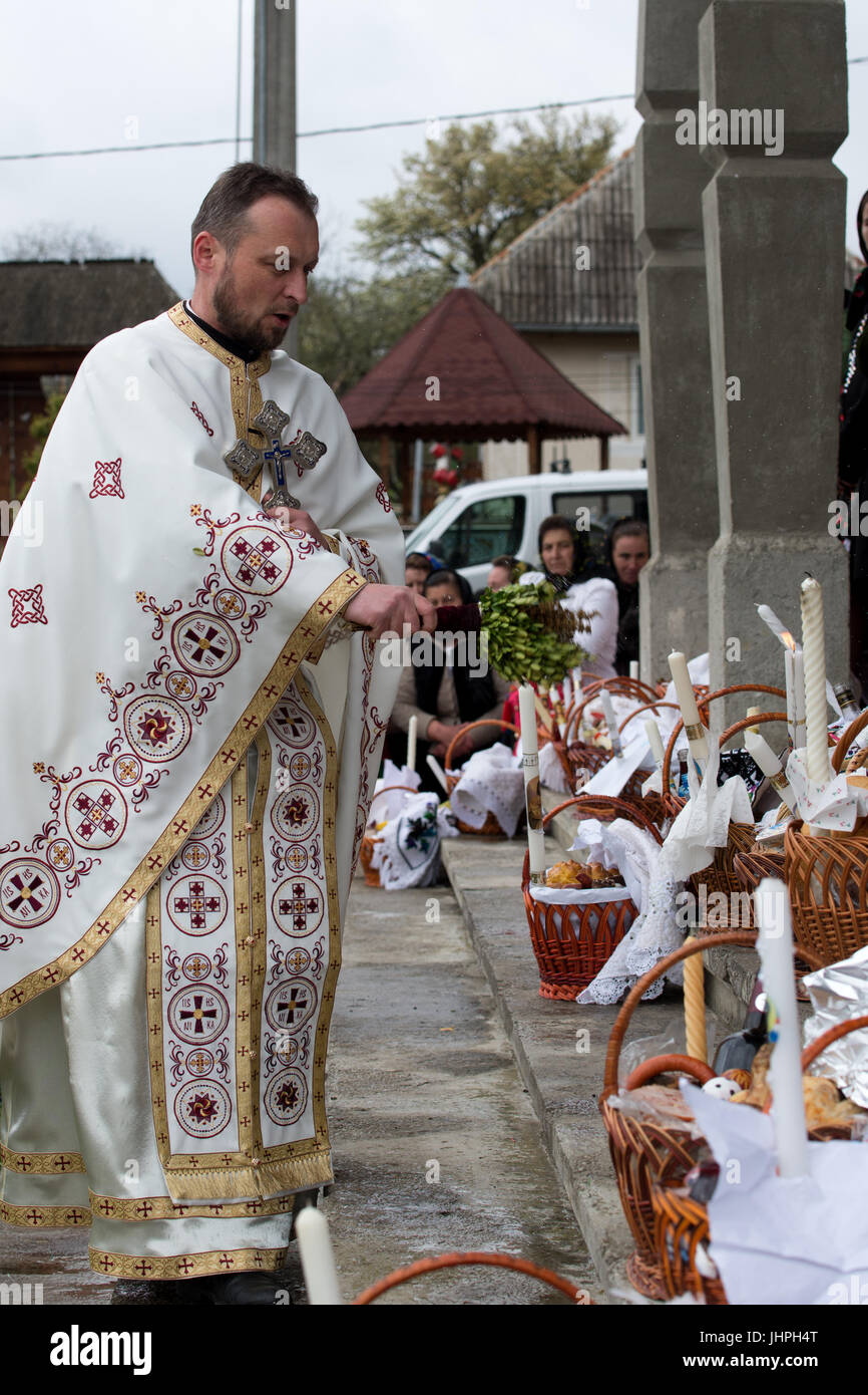 Un christina sacerdote ortodosso benedizione ceste di cibo dopo eeaster massa, villaggio di breb, distretto di maramures, Romania Foto Stock