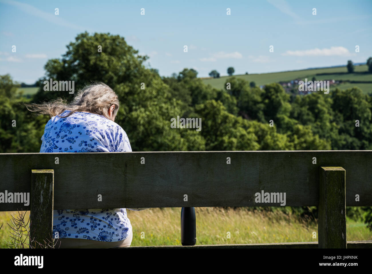 Pensionati anziani donna seduta su una panchina, godendo di una vista incantevole su una giornata di sole. Regno Unito Foto Stock