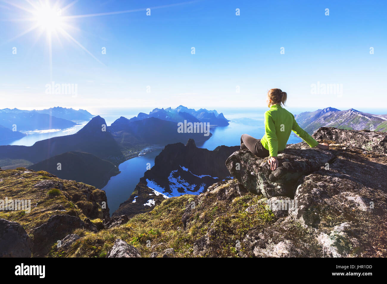 Donna escursionista di relax presso la cima della montagna e guardando una vista incredibile di un fiordo norvegese sull isola di Senja, nel nord della Norvegia Foto Stock