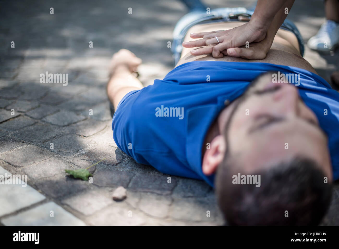 Ragazza rendendo la rianimazione cardiopolmonare per un inconscio guy dopo un attacco di cuore Foto Stock