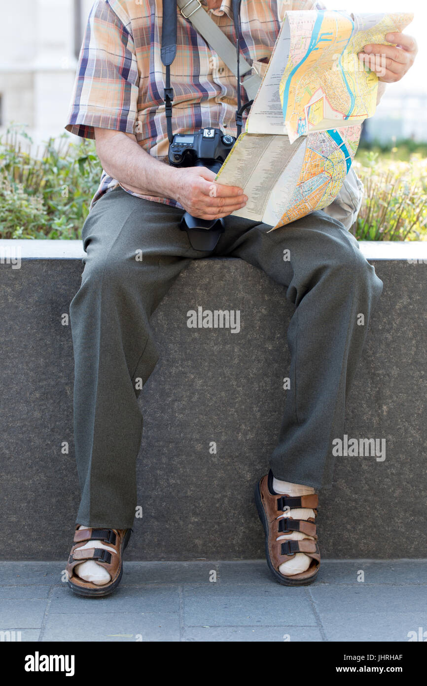 Anziano pensionato in calze e sandali ricerca destinazione sulla mappa in posizione di parcheggio Foto Stock