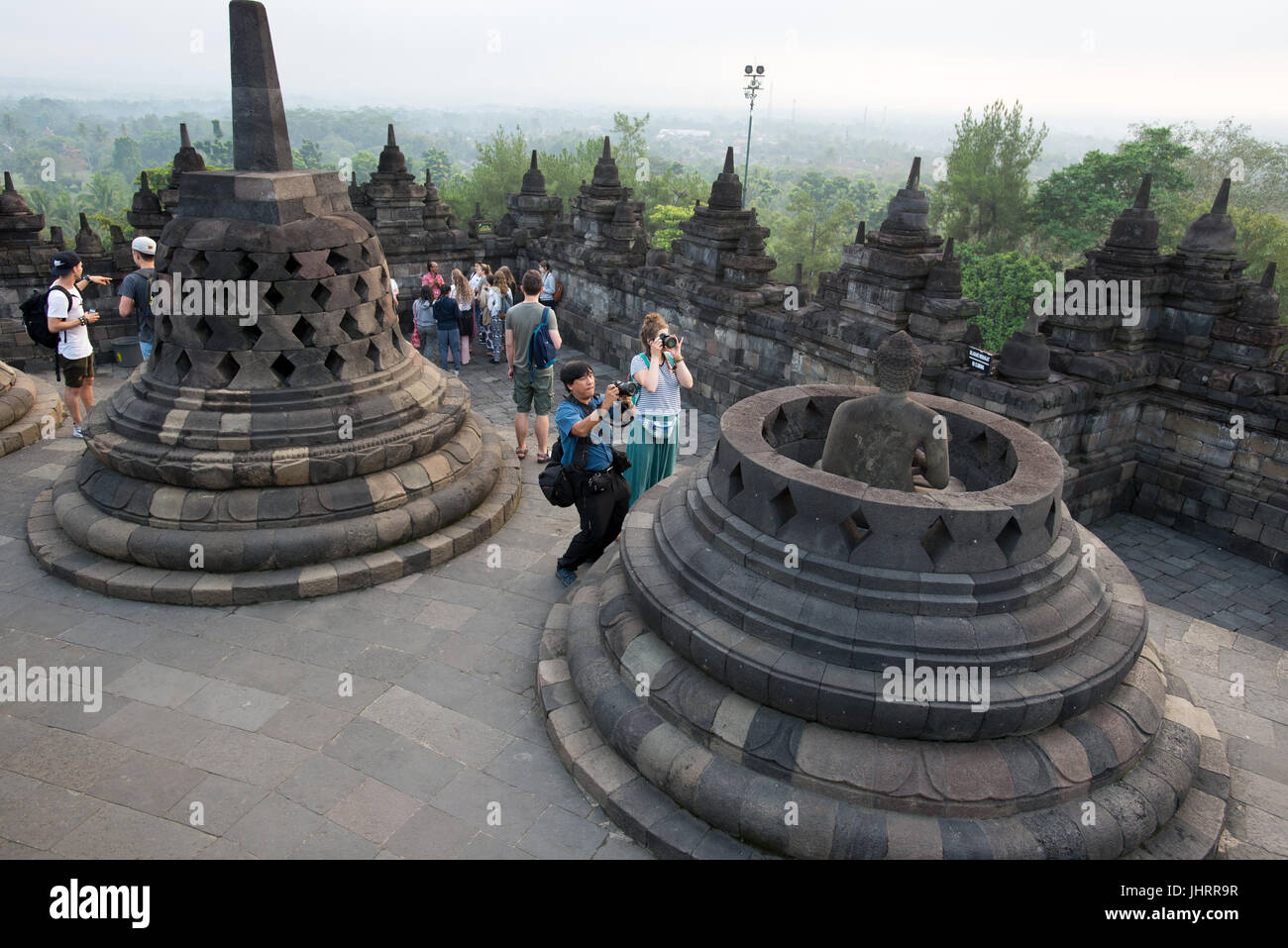 I turisti sono di scattare una foto di invincibile statua del Buddha in un aperto stupa, Tempio di Borobudur Java Indonesia. Foto Stock