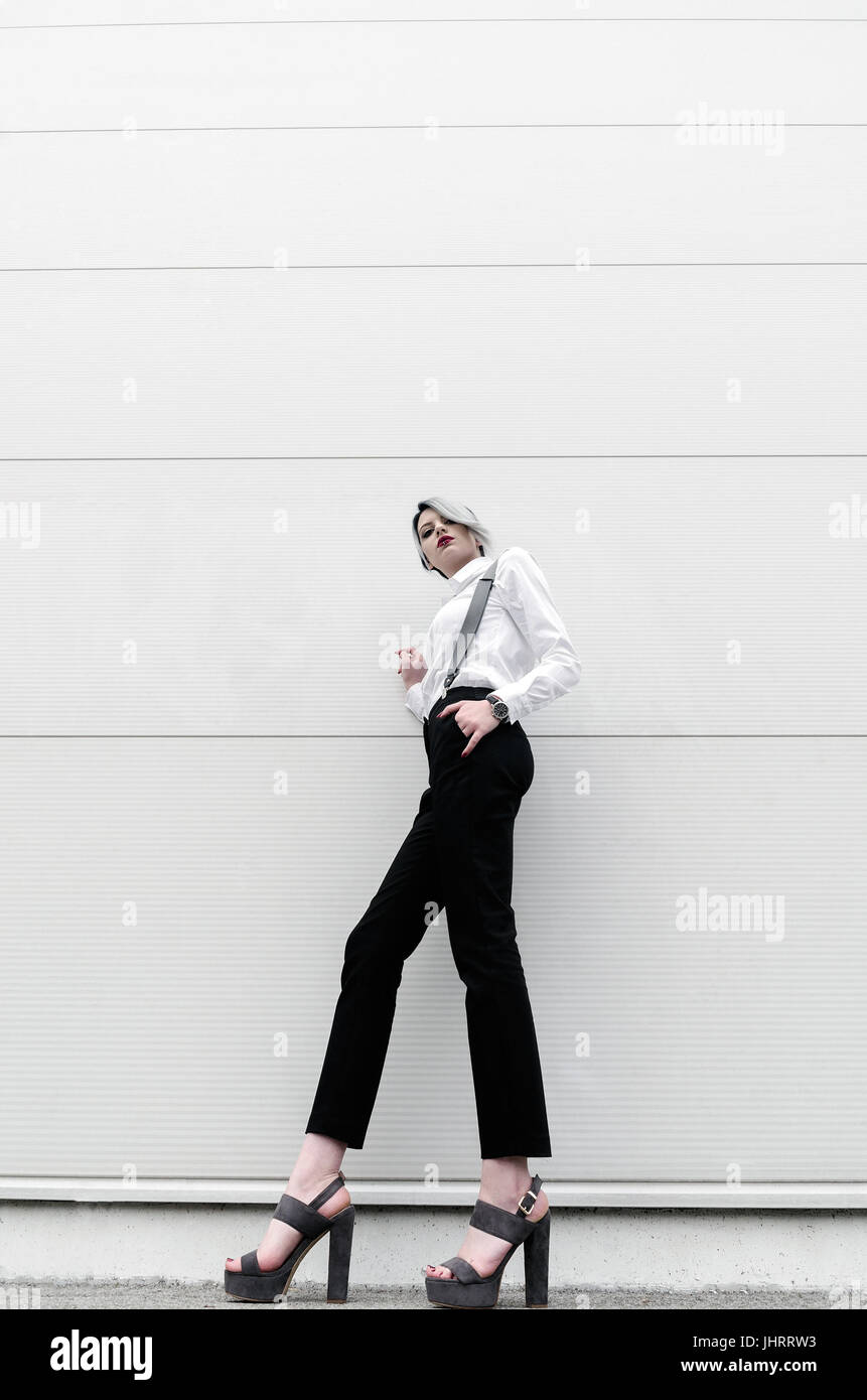 Moda giovane donna con gambe lunghe in posa sul muro bianco Foto Stock
