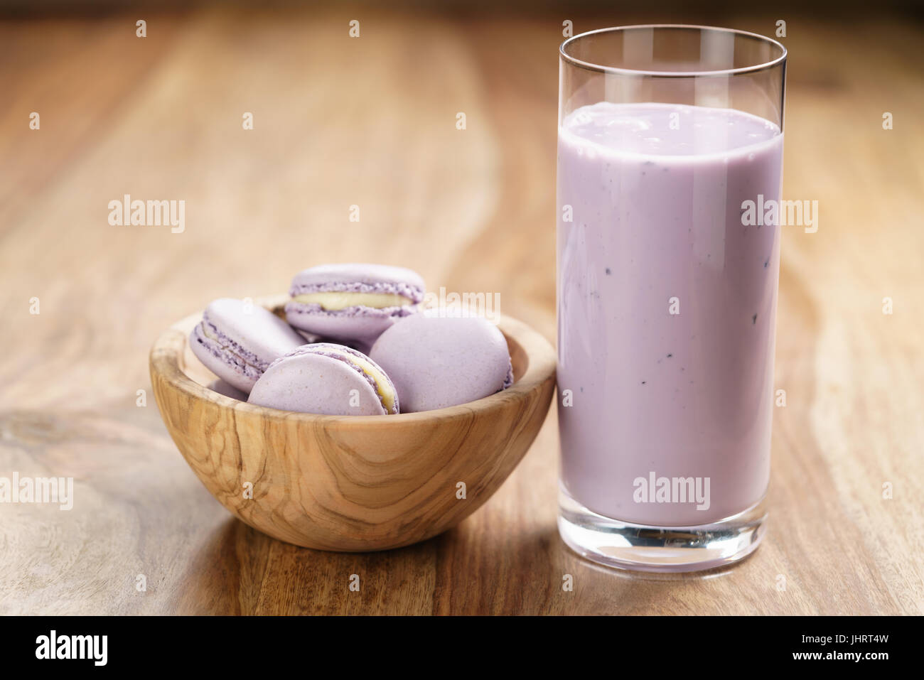 Violetta macarons nella ciotola di legno con mirtillo yogurt sul tavolo di legno Foto Stock