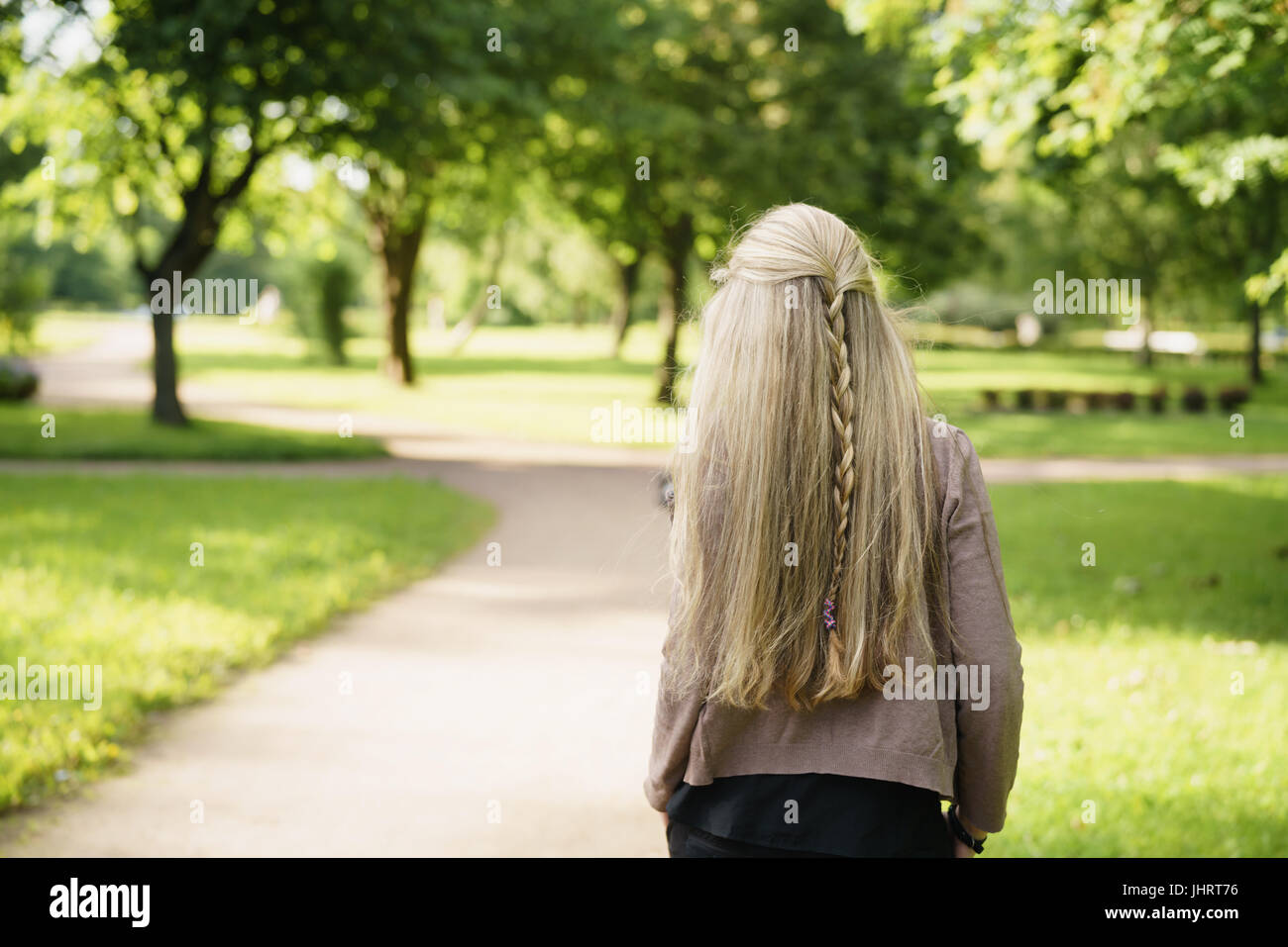 Teen ragazza nel parco verde da dietro nella soleggiata sera d'estate Foto Stock