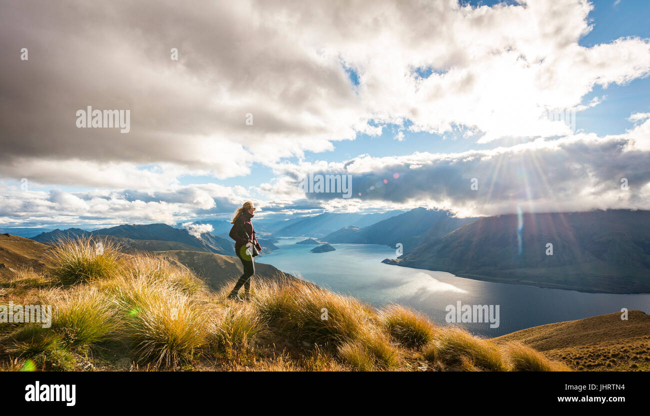 Escursionista femmina guardando il lago, lago Wanaka e paesaggio di montagna, Istmo di picco, Otago, Isola del Sud, Nuova Zelanda Foto Stock