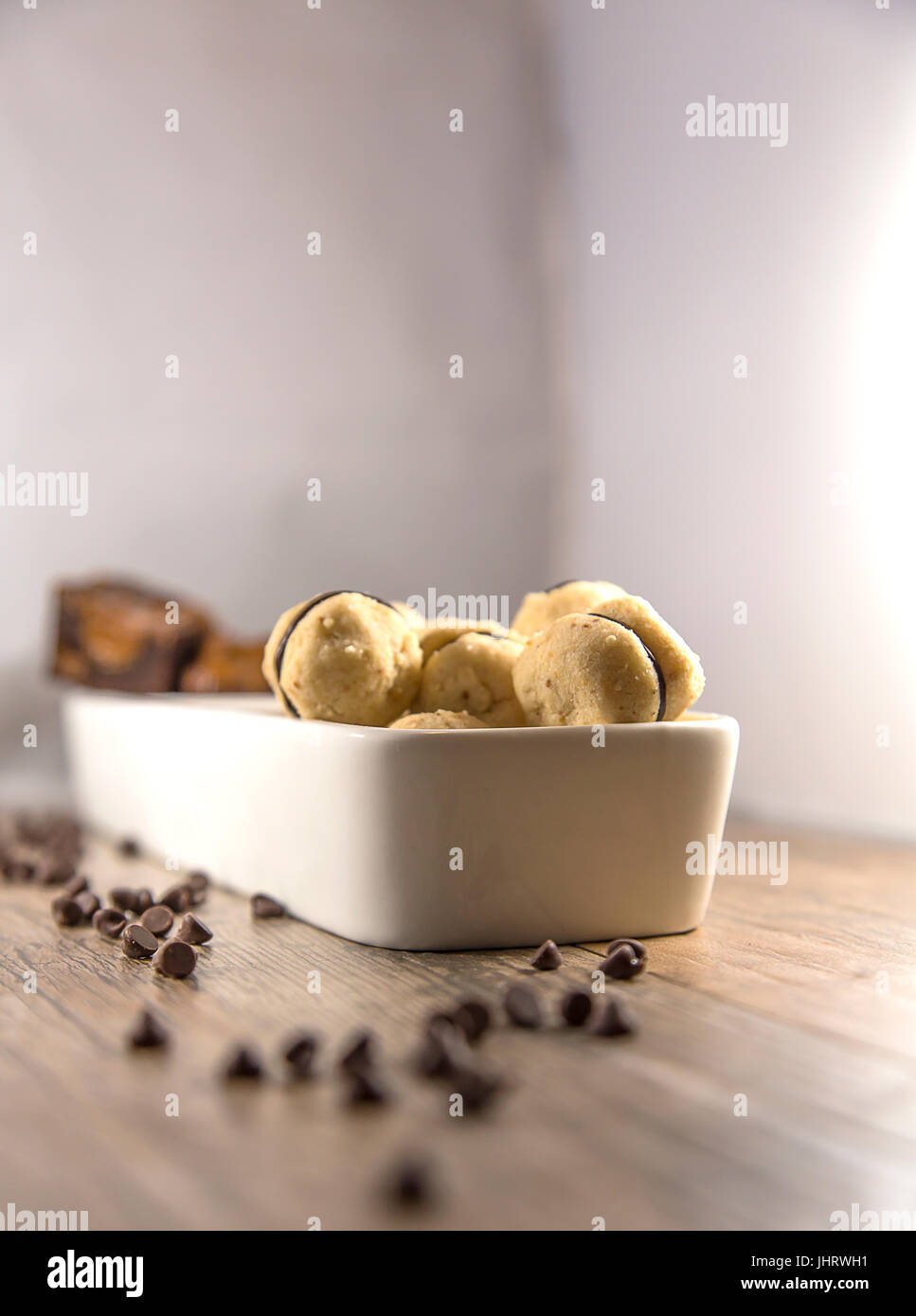 Bite-size cookie visualizzati in bianco di un piatto di portata, con scaglie di cioccolato. Sfondo di legno e la profondità di campo Foto Stock