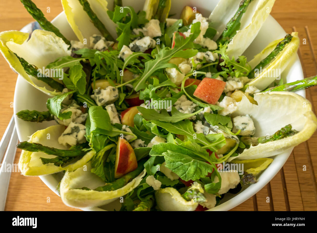 Insalata estiva servita in stoviglie bianco ciotola, con rucola, cicoria, radicchio, asparagi, nettarine, il roquefort e di vinaigrette a base di limone Foto Stock
