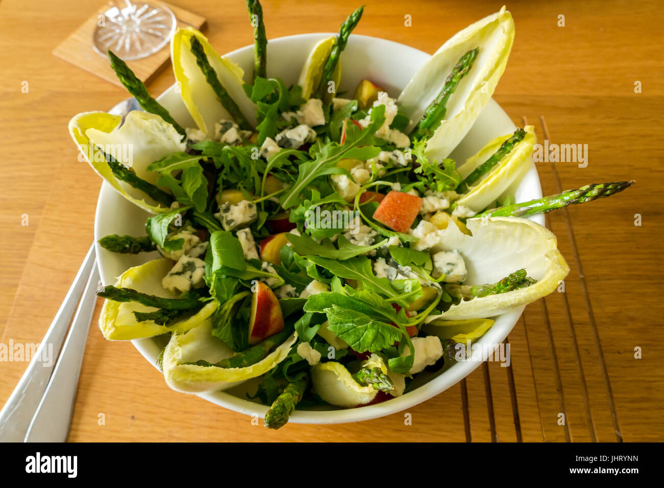 Insalata estiva servita in stoviglie bianco ciotola, con rucola, cicoria, radicchio, asparagi, nettarine, il roquefort e di vinaigrette a base di limone Foto Stock
