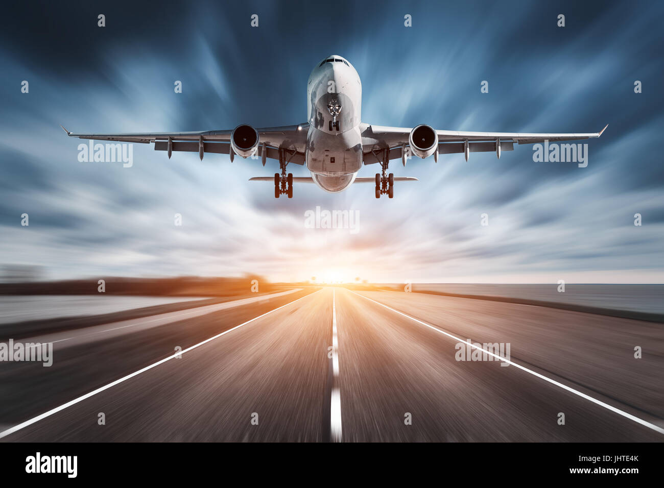 Aeroplano e road con motion blur effetto al tramonto. Paesaggio con passeggero aereo è volare sopra la strada asfaltata e cielo nuvoloso. Il piano commerciale Foto Stock