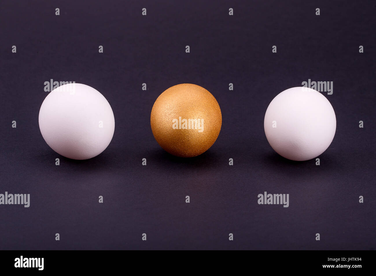 Una Golden Egg con due bianco su sfondo nero. Foto Stock