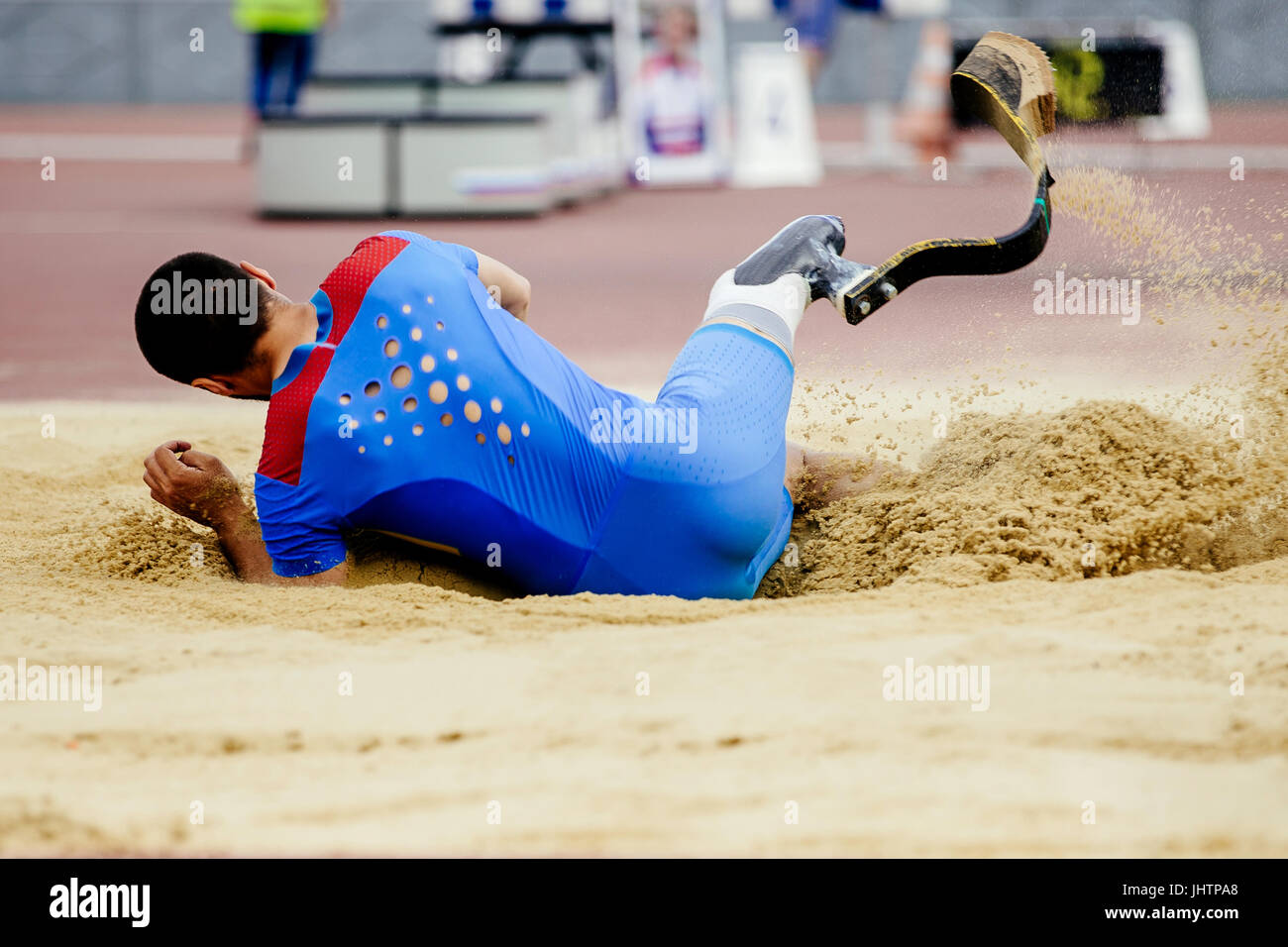 Salto in lungo atleta paralimpico di atterraggio disabili in sabbia Foto Stock