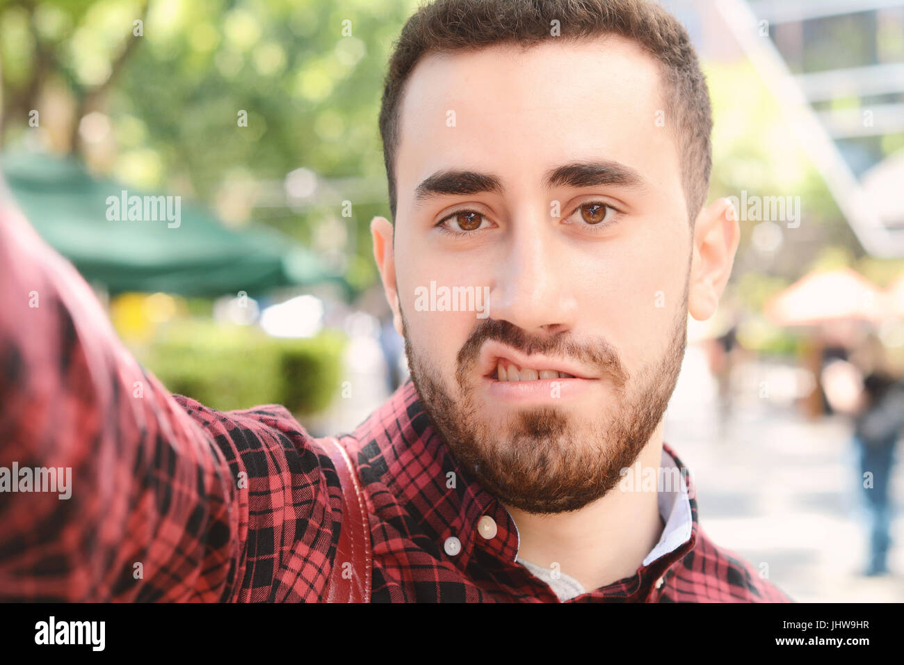 Giovane uomo latino tenendo un selfie. Scena urbana. All'esterno. Foto Stock