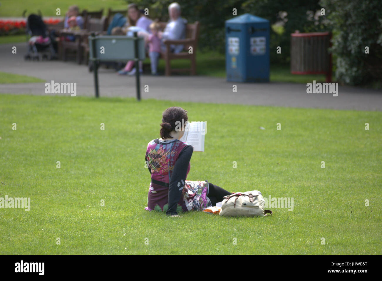 Botanic Gardens Glasgow giornata soleggiata giovane ragazza adolescente la lettura di prenotare da soli Foto Stock