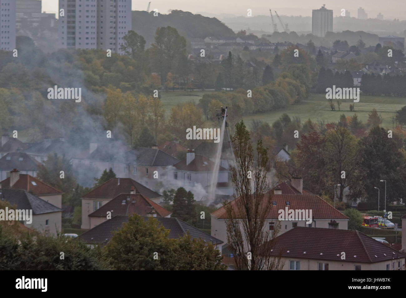I vigili del fuoco di combattere il fuoco alto sulla scala di Glasgow knightswood borgo casa di fuoco giornata di sole Foto Stock