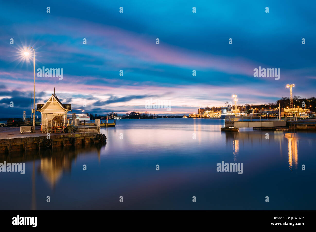 Helsinki, Finlandia. Paesaggio con città Pier, Jetty in inverno all'alba o al tramonto del tempo. Cielo blu riflessa nel mare tranquillo della superficie dell'acqua. Ormeggio in luce Foto Stock