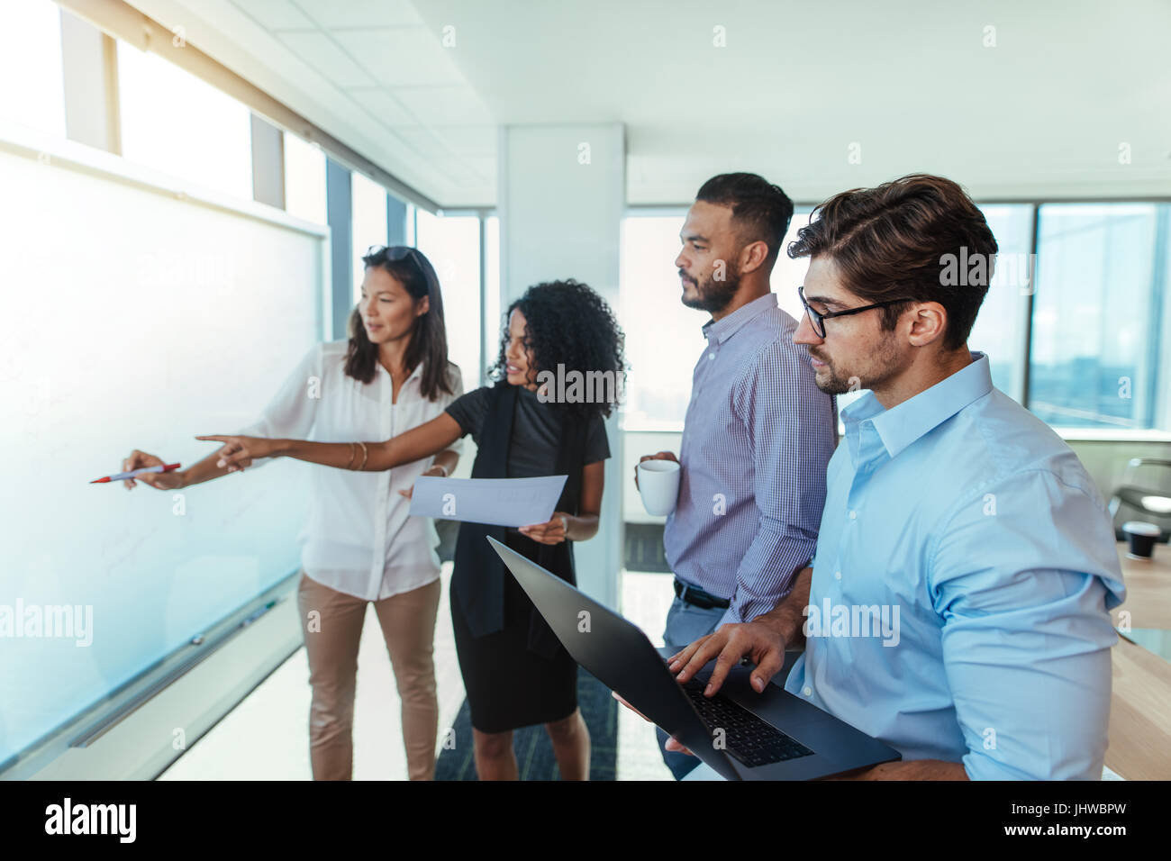 Le donne imprenditrici a discutere idee di business in sala riunioni con i loro colleghi. Giovani investitori aziendali presentando un piano aziendale su una lavagna bianca Foto Stock