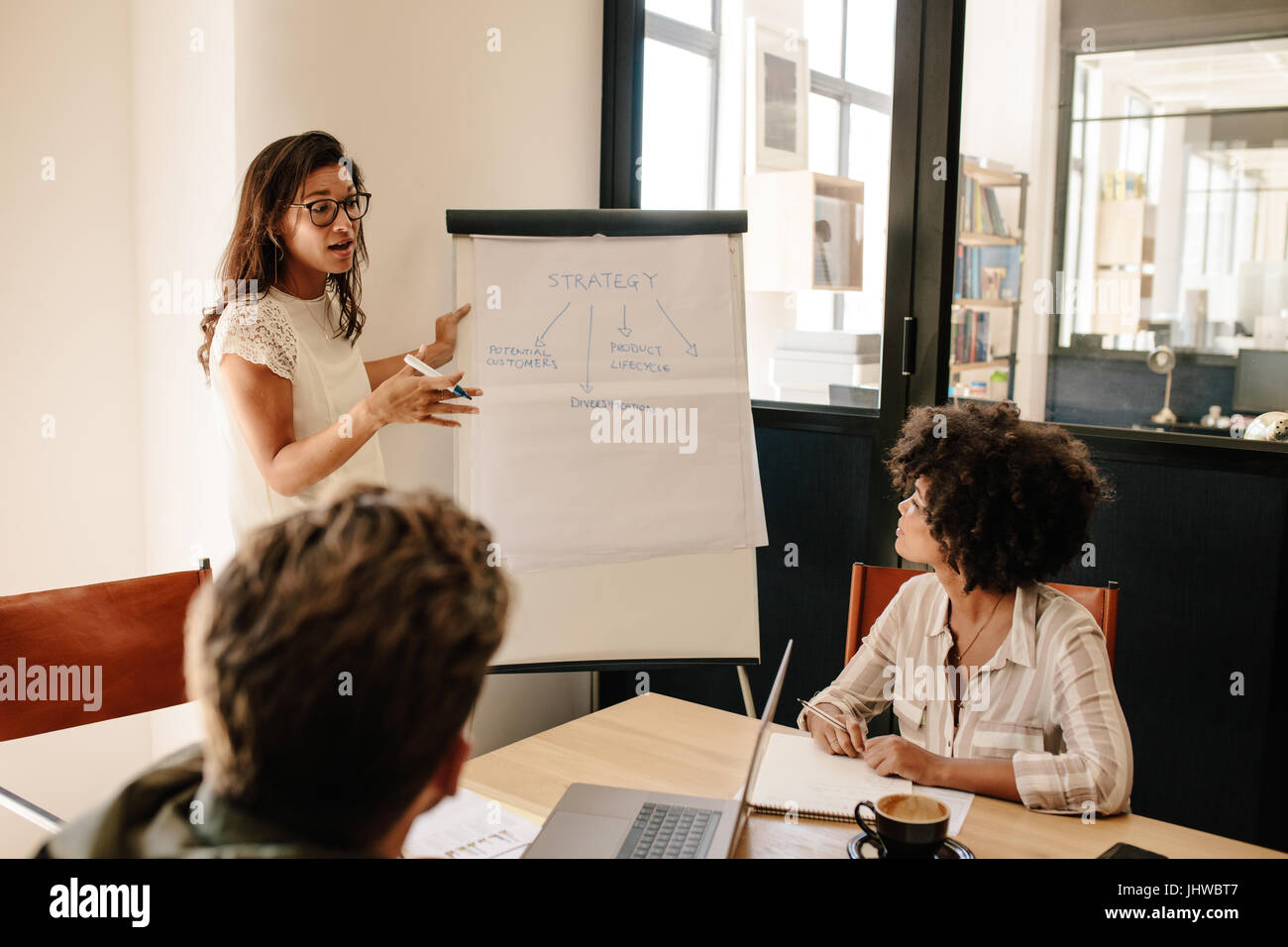Donna che spiega le nuove strategie per i colleghi durante la riunione. Riunione di imprenditori in office board camera per nuova discussione del progetto.. Foto Stock