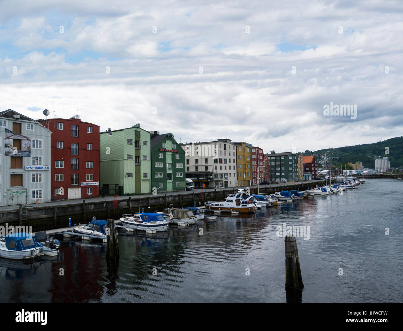 Vista lungo fiume Nidelva ai pontili Bryggene negozi su Fjordgate Trondheim in Norvegia con ormeggiati motoscafi Foto Stock