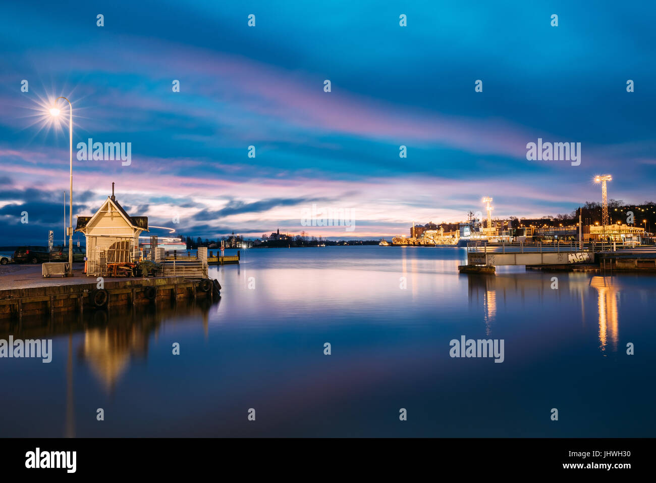 Helsinki, Finlandia - 9 Dicembre 2016: il paesaggio della città di Pier, Jetty in inverno gli orari di alba e tramonto del tempo. Cielo blu riflessa nel mare tranquillo della superficie dell'acqua. Foto Stock