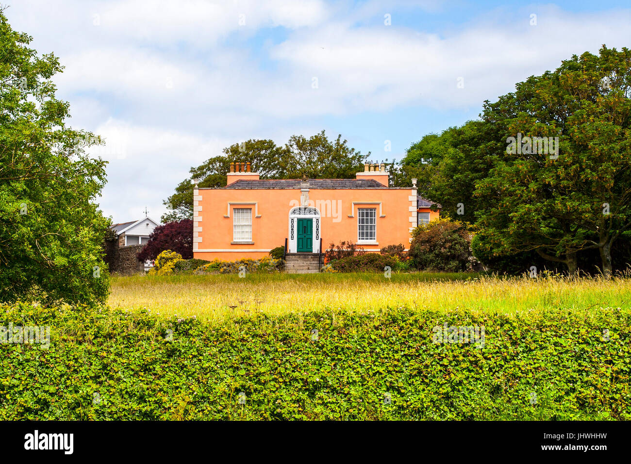 Orange bungalow casa sullo sfondo di un prato verde circondato da boccole Foto Stock
