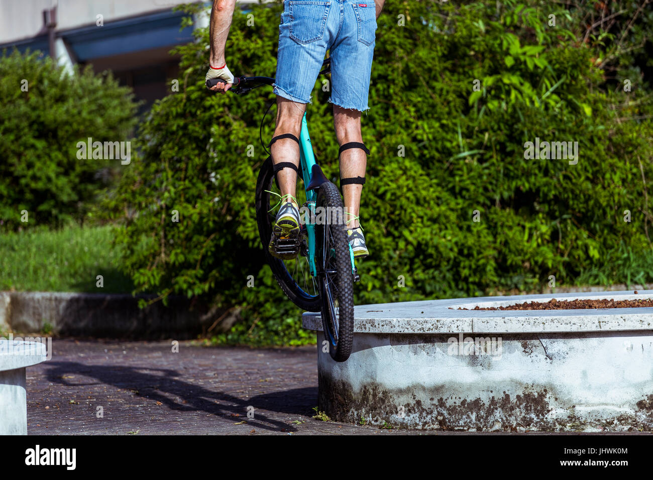Ciclista su una mountain bike saltando su una decorazione di pietra nella città. Foto Stock