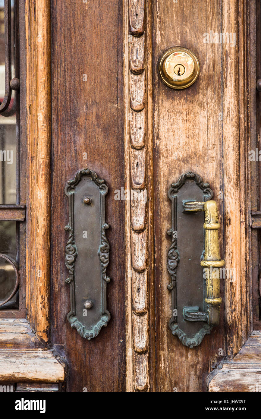 Primo piano di legno vecchio porta esterna con maniglie in ottone Foto Stock
