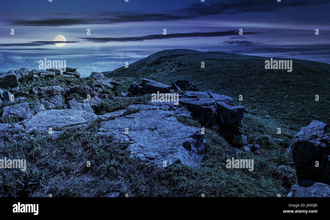 Enormi massi sul bordo della collina a mezzanotte. Il bel tempo in estate paesaggio montano di notte nella luce della luna piena Foto Stock