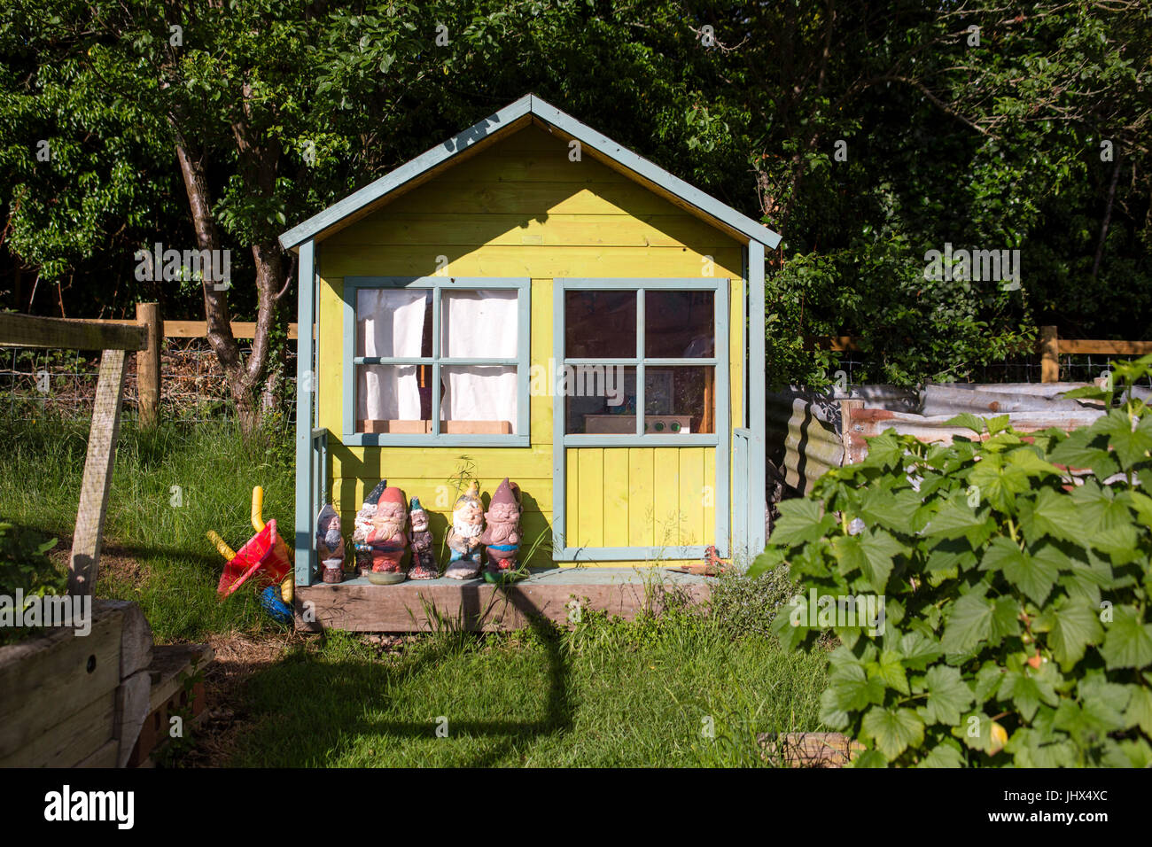 Un piccolo dipinto di casa in legno per far giocare i bambini con le statue di gnome per la decorazione in un giardino del Regno Unito. Foto Stock