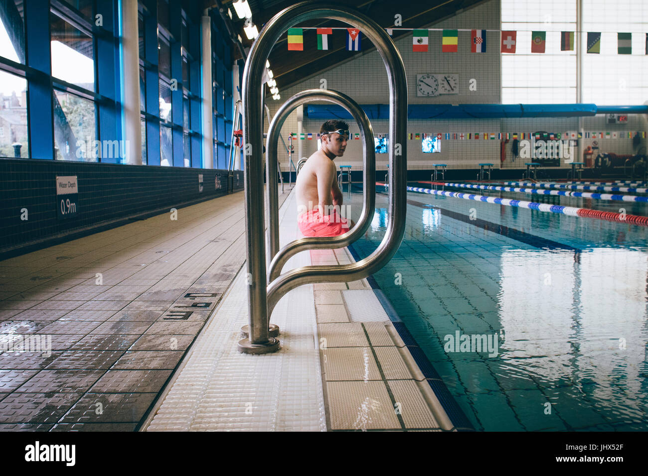 Quadriplegic nuotatore seduta sul bordo della piscina. Foto Stock