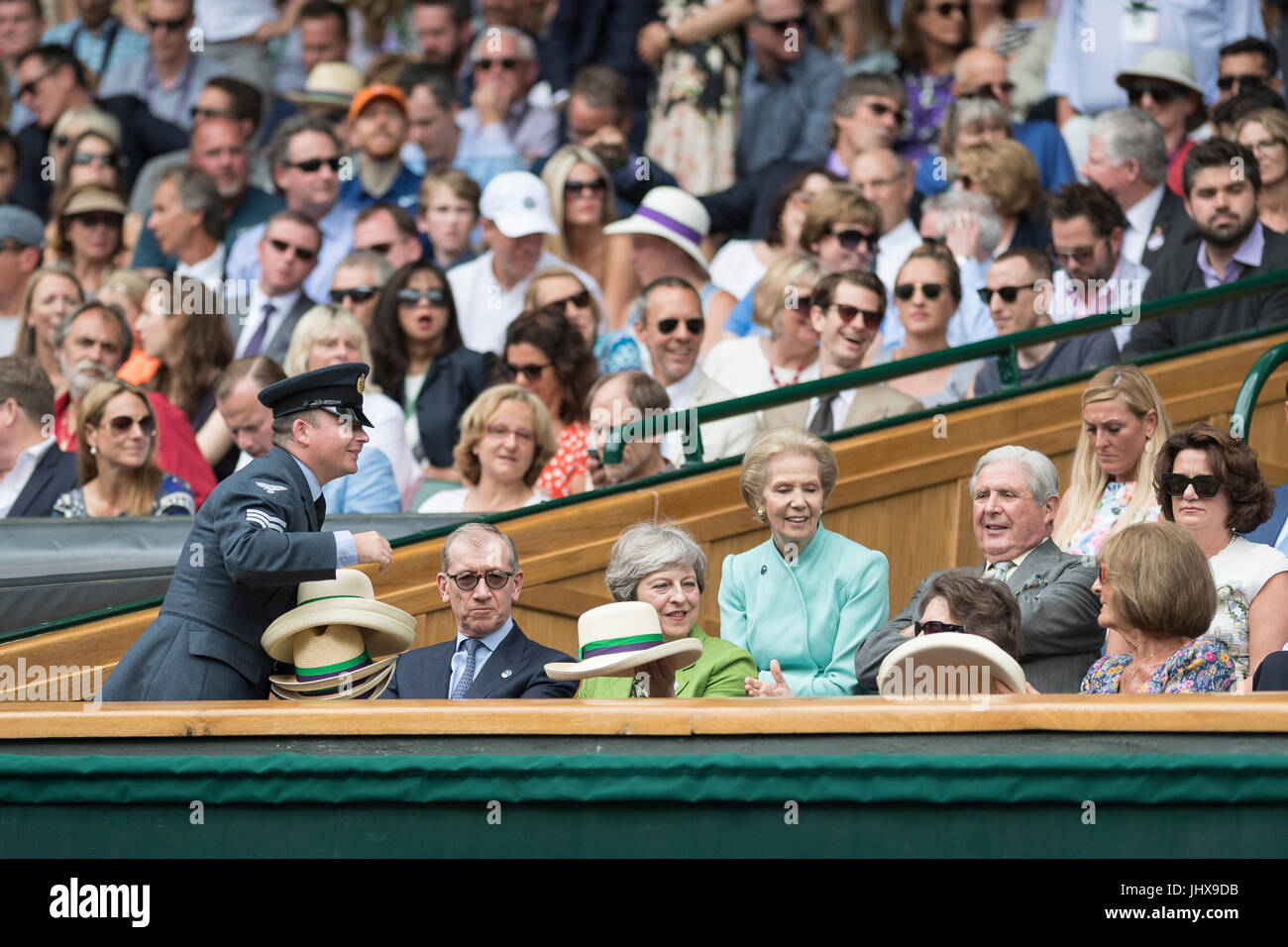 Il torneo di Wimbledon, Londra, Regno Unito. 16 Luglio, 2017. Il torneo di Wimbledon Tennis Championships 2017 tenutosi presso il All England Lawn Tennis e Croquet Club di Londra, Inghilterra, Regno Unito. Singolo maschile - finale Roger Federer (SUI) [3] v Marin CILIC (CRO) [7] sul Centre Court. Il primo ministro Theresa Maggio guarda la partita dal Royal Box con il marito Filippo. Ella assiste uno steward per distribuire Panama cappelli con gli altri ospiti nel Royal Box. Credito: Duncan Grove/Alamy Live News Foto Stock