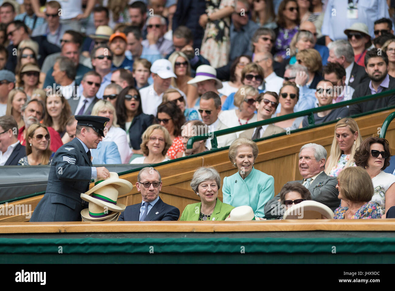 Il torneo di Wimbledon, Londra, Regno Unito. 16 Luglio, 2017. Il torneo di Wimbledon Tennis Championships 2017 tenutosi presso il All England Lawn Tennis e Croquet Club di Londra, Inghilterra, Regno Unito. Singolo maschile - finale Roger Federer (SUI) [3] v Marin CILIC (CRO) [7] sul Centre Court. Il primo ministro Theresa Maggio guarda la partita dal Royal Box con il marito Filippo. Ella assiste uno steward per distribuire Panama cappelli con gli altri ospiti nel Royal Box. Credito: Duncan Grove/Alamy Live News Foto Stock