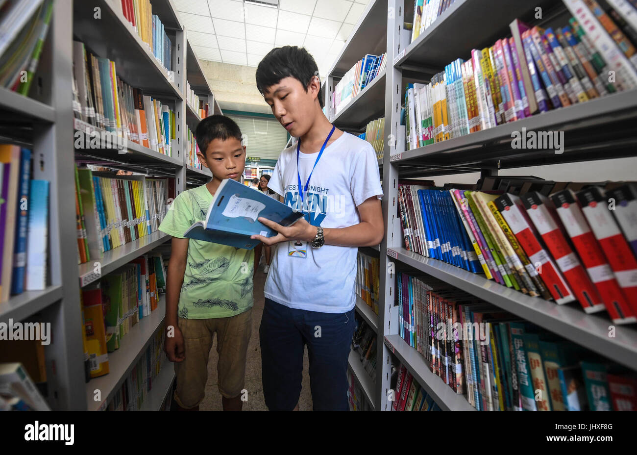 Gucheng cinese nella provincia di Hebei. 17 Luglio, 2017. Un ragazzo seleziona prenota con l aiuto di un volontario (R) nella contea di Gucheng, nel nord della Cina di nella provincia di Hebei, 17 luglio 2017. In questa vacanza estiva, la biblioteca della contea di Gucheng fornisce ai bambini con la lettura di classi, dove possono leggere più di 90.000 libri con la guida di volontari. Credito: Li Xiaoguo/Xinhua/Alamy Live News Foto Stock