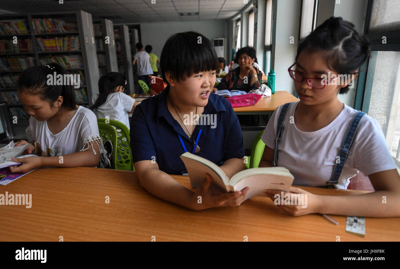 Gucheng cinese nella provincia di Hebei. 17 Luglio, 2017. Una ragazza legge con la guida di un volontario (C) nella contea di Gucheng, nel nord della Cina di nella provincia di Hebei, 17 luglio 2017. In questa vacanza estiva, la biblioteca della contea di Gucheng fornisce ai bambini con la lettura di classi, dove possono leggere più di 90.000 libri con la guida di volontari. Credito: Li Xiaoguo/Xinhua/Alamy Live News Foto Stock